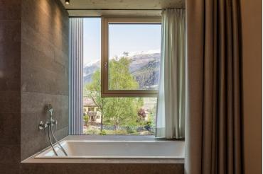 Die Badewanne an der Fassade mit Panoramablick über die Garten- und Poollandschaft der Juniorsuite Design